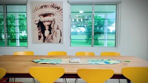 Une salle de conférence avec une longue table en bois, des chaises jaunes et une grande fenêtre donnant sur un paysage verdoyant.