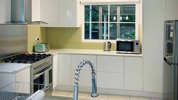 Une cuisine moderne dotée d’appareils électroménagers en acier inoxydable, d’un évier à deux bacs et de luminaires suspendus.