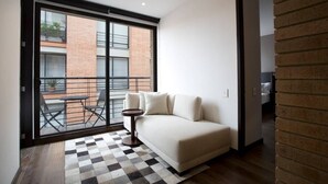 Un saló modern amb un sofà, una catifes a quadres i vista a un edifici de maó a través d'una porta de vidre.