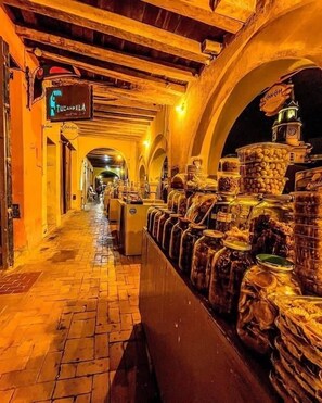 Ein Korridor mit Regalen voller Einmachgläser, Holzbalken an der Decke und einem Schild, das auf ein Restaurant hinweist.