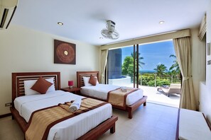 Ein Hotelzimmer mit zwei Betten, einem großen Fenster mit Blick auf Palmen und das Meer, sowie einem Balkon mit einem Stuhl.