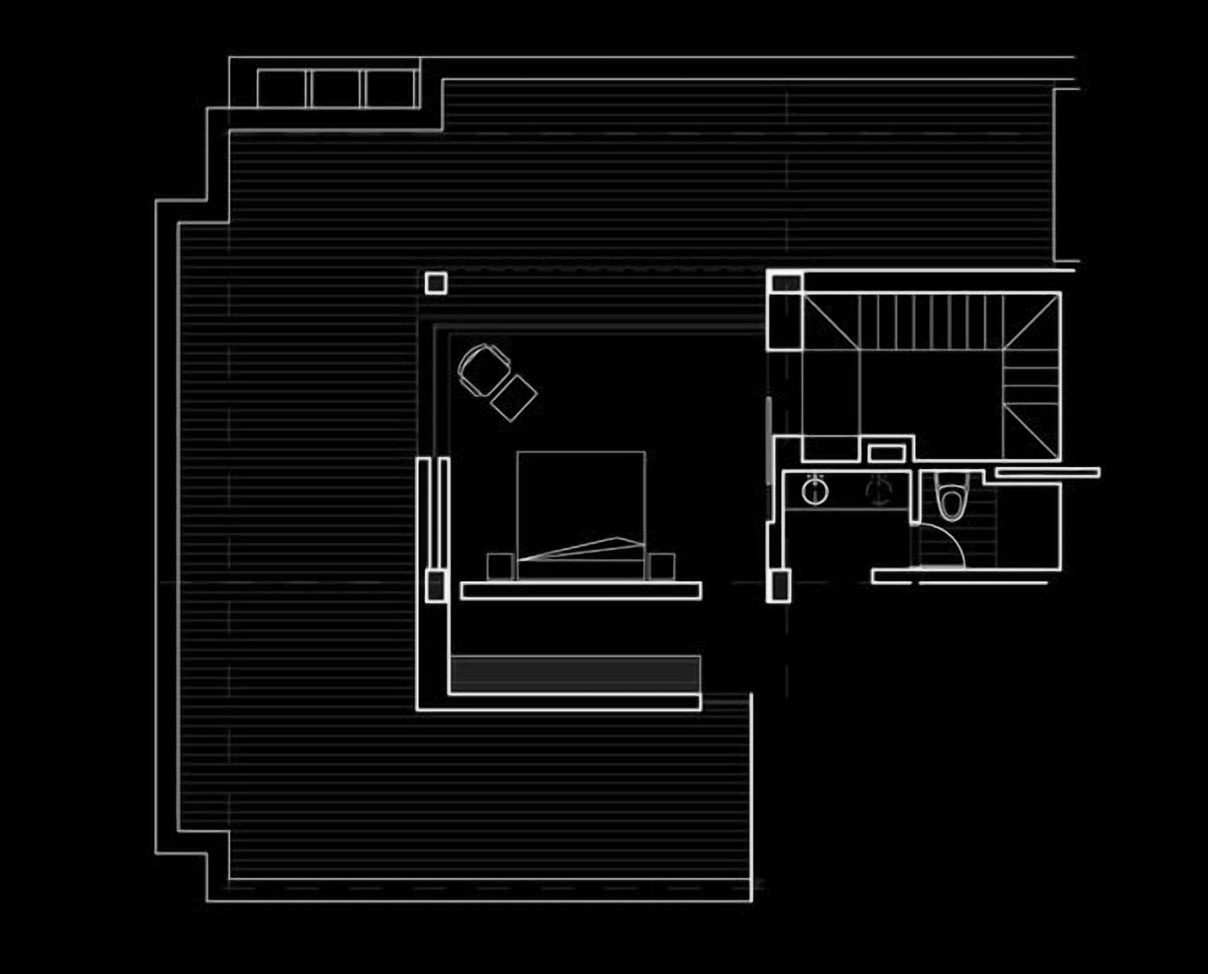 En planritning över ett hotell med ett stort centralt område, ett mindre rum med en säng och ett litet köksutrymme.
