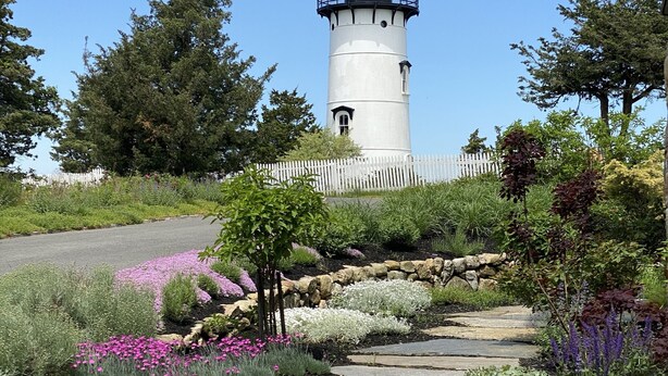 A lighthouse surrounded by a landscaped garden with a stone pathway. - Beautiful Carriage House on the Chop (Oak Bluffs)