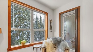 Une pièce confortable avec une grande fenêtre, une porte et une petite table ronde.
