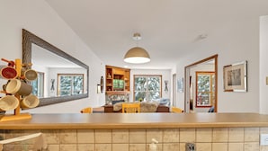 Une cuisine dotée d’un grand îlot central, un coin repas avec un canapé et une table, et un grand miroir.