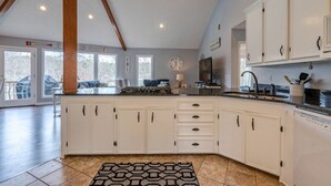 A spacious kitchen with white cabinets, a large island, and a dining area with a view.
