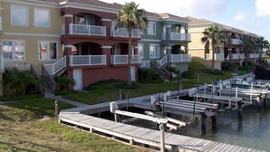 A row of multi-story buildings with balconies, a dock, and a marina. - Vitamin Sea- 40 HT (Laguna Vista)