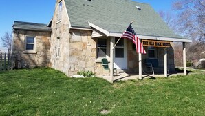 En byggnad av sten med ett grönt tak, en amerikansk flagga och en skylt med texten ”The Old Rock House”.