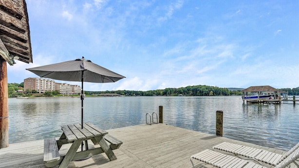 Une jetée en bois avec une table de pique-nique et un parasol, d’où l’on a vue sur un lac paisible, avec un bateau amarré sur la droite.