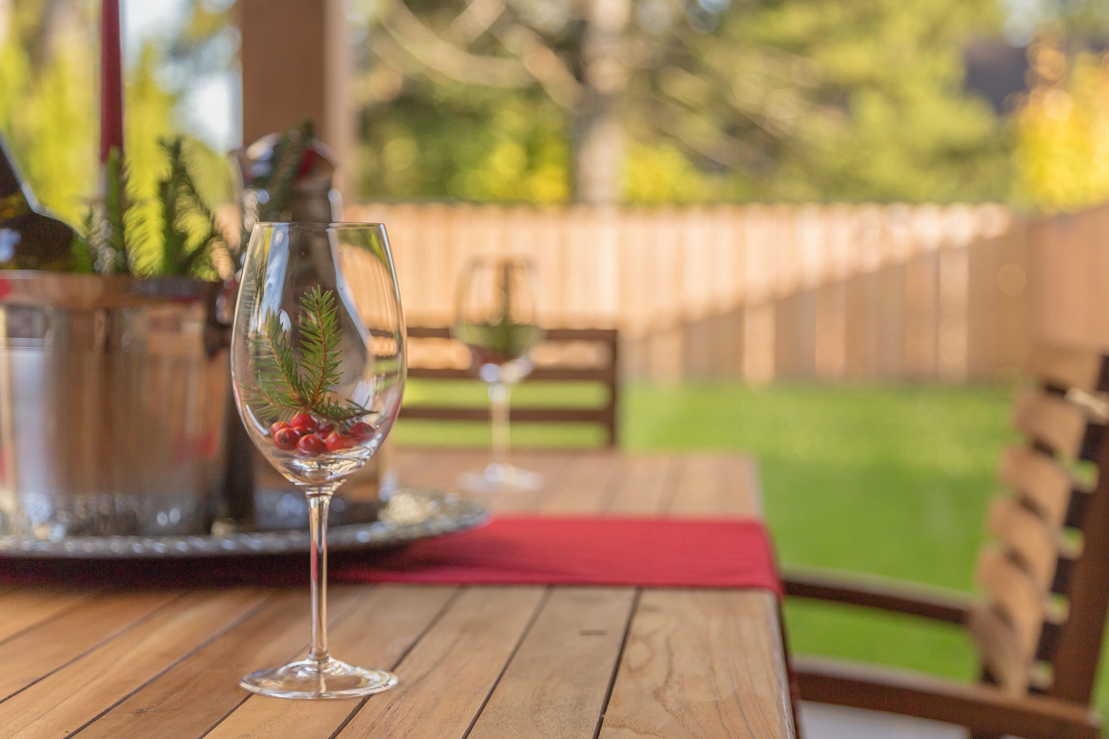 Uma mesa de madeira com um copo de vinho e um ramo decorativo de pinheiro.