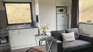 Ein gemütlicher Wohnraum mit Küchenzeile, einer Couch, einem Couchtisch und einer Decke.