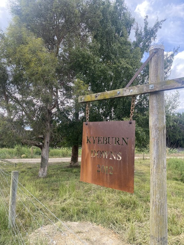 A weathered metal sign with the inscription "KYEBURN DOWNS 2012" mounted on a wooden post.