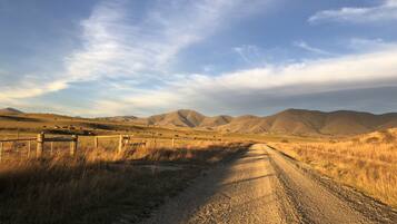A dirt road leading through a hilly landscape with mountains in the background.