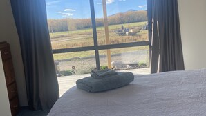 Ein Schlafzimmer mit einem großen Bett, Blick auf eine ländliche Gegend und einem hölzernen Schminktisch.