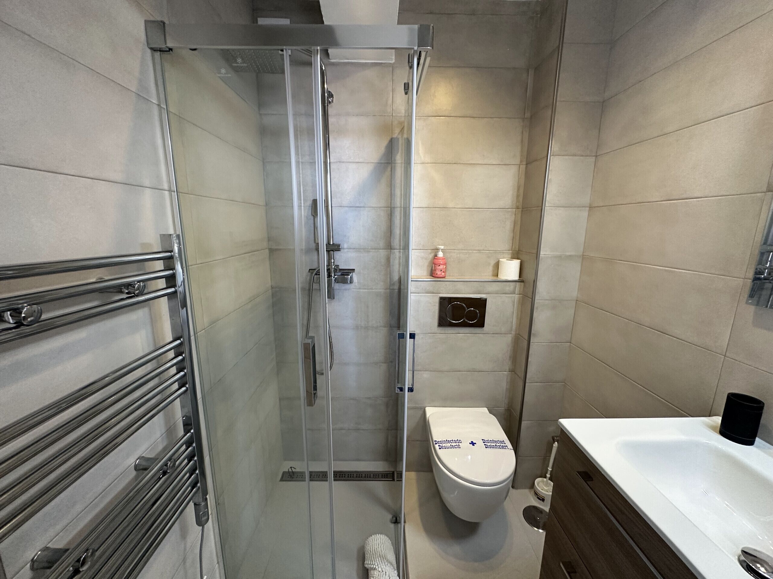 A bathroom with a glass-enclosed shower, a toilet, and a sink.