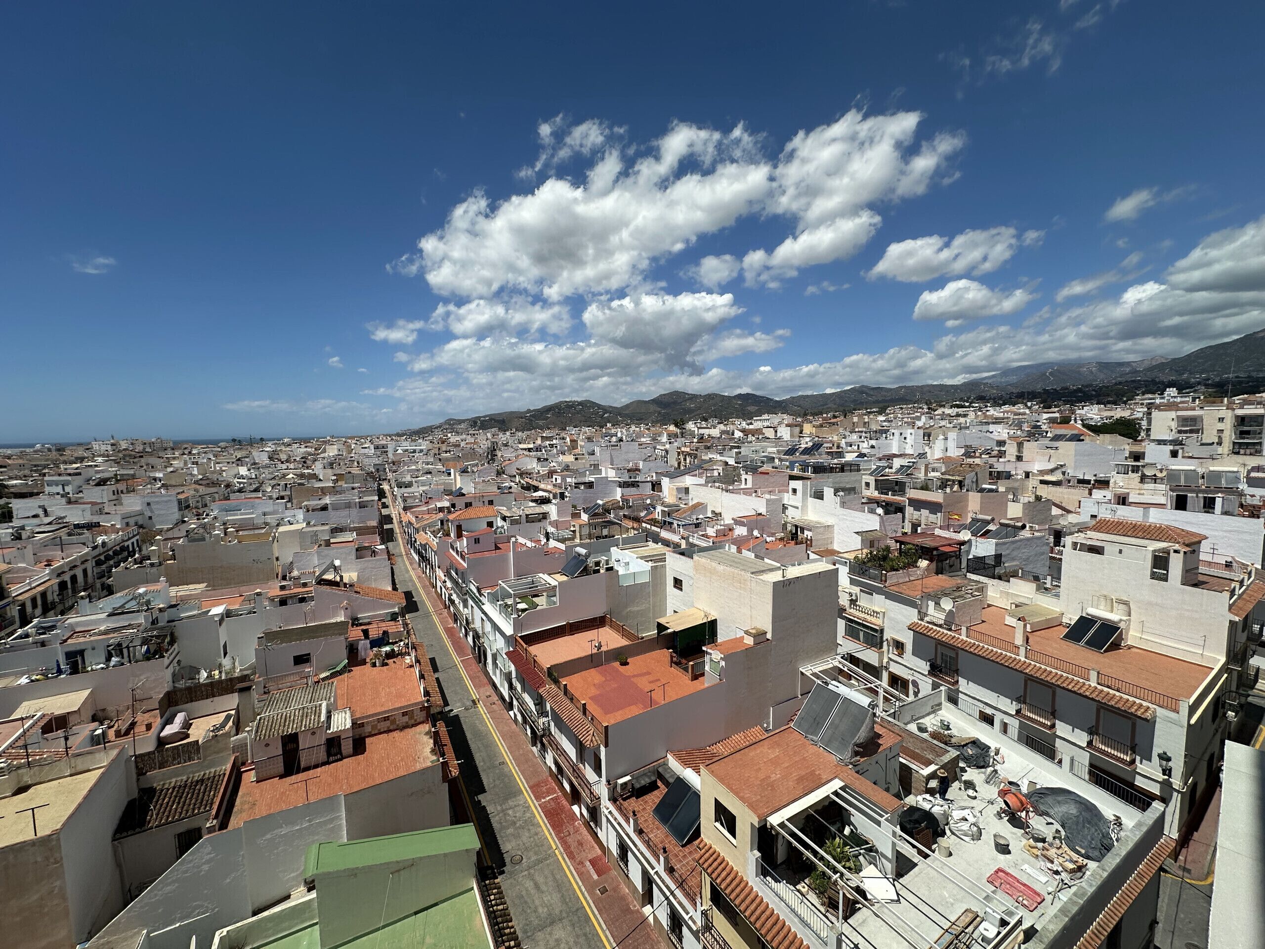 Une vue urbaine avec une large rue, des bâtiments aux toits plats et un ciel dégagé.