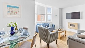 A modern living room with a glass dining table, striped armchair, and a grey sofa.