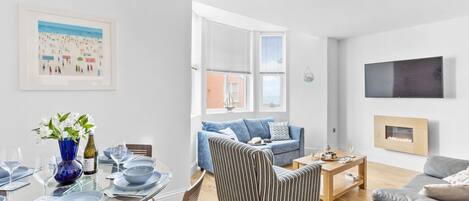 Ein modernes Wohnzimmer mit einem Glastisch, einem gestreiften Sessel und einem grauen Sofa.