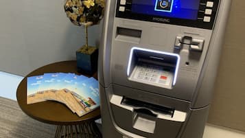 An ATM machine with a screen displaying a welcome message, card slot, and cash dispensing area.