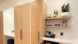 A modern kitchen with wooden cabinets, a built-in fridge, and a countertop with various items. - Cribs on Main (Prince Edward)
