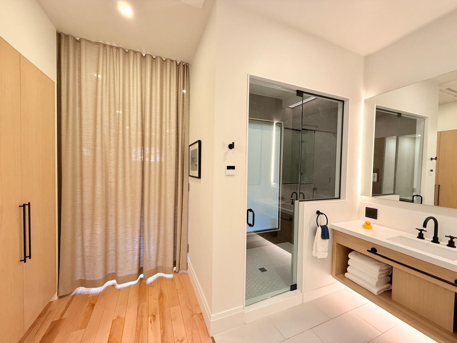 Un baño moderno con ducha, un espejo grande y un tocador con lavamanos.