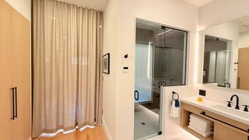 Un baño moderno con ducha, un espejo grande y un tocador con lavamanos.