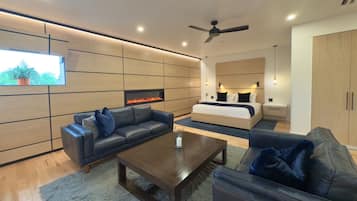 A modern living room with a fireplace, sofas, a coffee table, and a bed with a headboard.