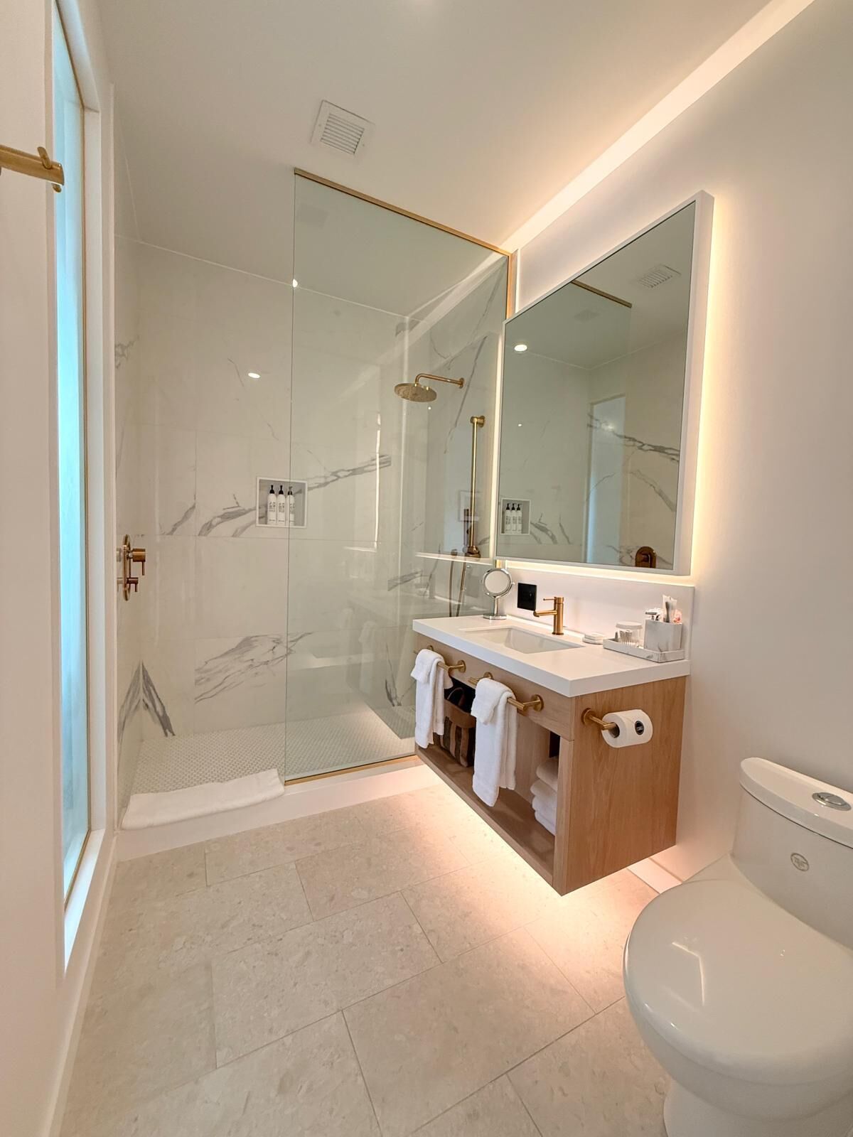 Un baño moderno con ducha de vidrio, un espejo grande y un inodoro.