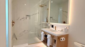 Un baño moderno con ducha de vidrio, un espejo grande y un inodoro.