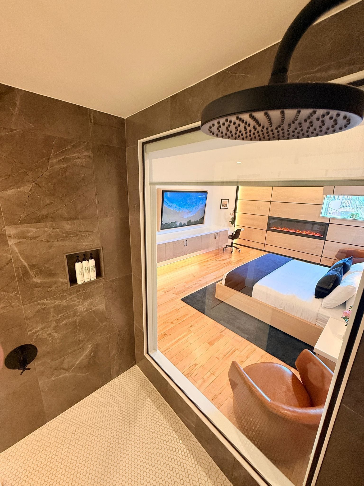 A modern bathroom with a large mirror, a shower area, and a toilet.