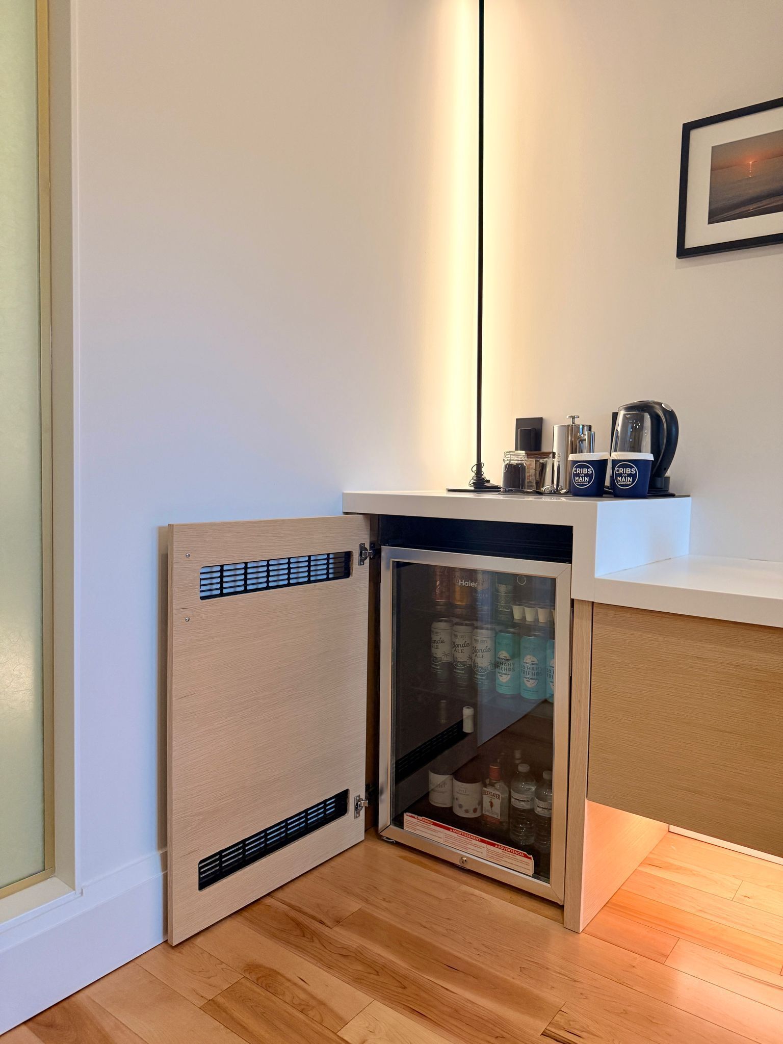 Een ruimtelijk kitchenette met een ingebouwde minibar, een koffiezetapparaat en een plank met merkbekers.