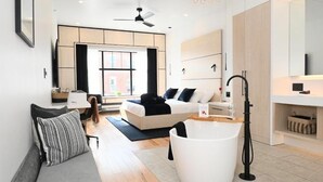A modern living room with a sofa, a white coffee table, and a large window. - Cribs on Main (Prince Edward)