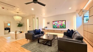 A modern living room with a large flat-screen TV, a ceiling fan, and a chandelier. - Cribs on Main (Prince Edward)