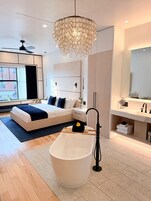 A modern bathroom with a freestanding bathtub, a large mirror, and a contemporary chandelier.