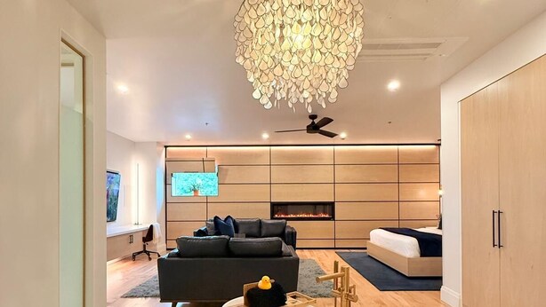 A modern living room with a large bathtub, a chandelier, and a fireplace. - Cribs on Main (Prince Edward)