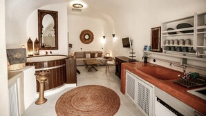 A compact kitchen with a central island, a built-in sink, and a dining area with a sofa and coffee table.