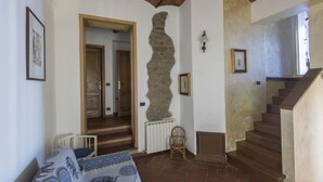 Una stanza con una parete in pietra, una scala in legno e un letto con copriletto decorato.