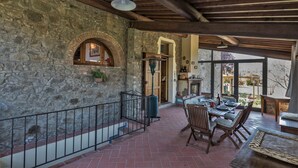 Un patio con pareti in pietra, un tavolo e sedie in legno, una ringhiera metallica e vista sull'esterno.