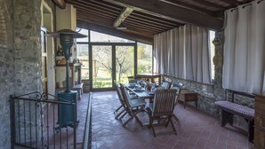 Un portico coperto con pareti in pietra, un tavolo di legno e sedie.