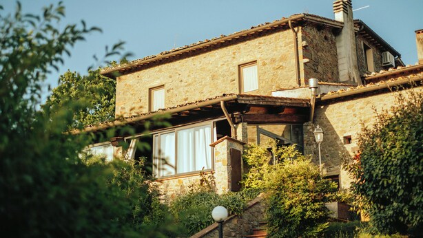 Un edificio rustico in pietra con tetto spiovente, travi in legno e un piccolo balcone.