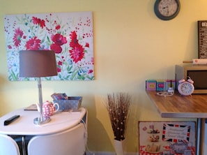 Cozy room with a desk, lamp, and floral painting, perfect for a relaxing stay.