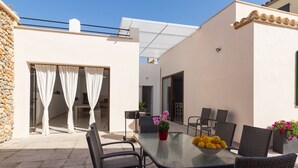 An outdoor patio with a glass table, wicker chairs, and a bowl of fruit. - Son Siurana - Newtly built town house with pool in Ariany (Ariany)