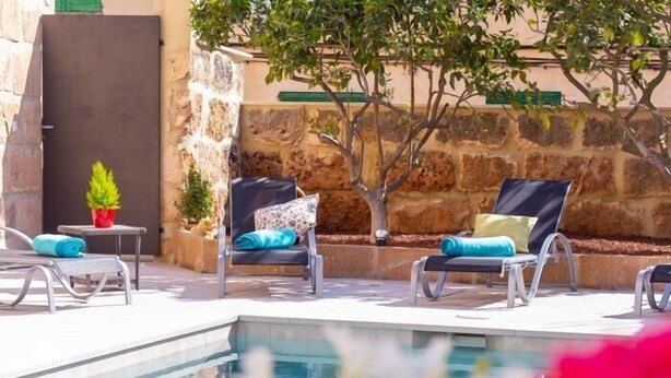 A poolside area with lounge chairs and a stone wall backdrop. - Son Siurana - Newtly built town house with pool in Ariany (Ariany)