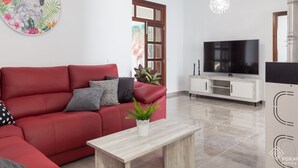 A modern living room with a red sofa, a wooden coffee table, a TV on a white cabinet, and a large window with a view of flamingos. - Son Siurana - Newtly built town house with pool in Ariany (Ariany)