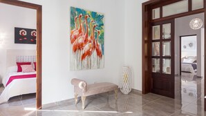 A spacious room with a large painting of flamingos, a bench, and a door leading to another room. - Son Siurana - Newtly built town house with pool in Ariany (Ariany)