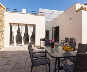 An outdoor patio with a glass table, wicker chairs, and a bowl of fruit. - Son Siurana - Newtly built town house with pool in Ariany (Ariany)