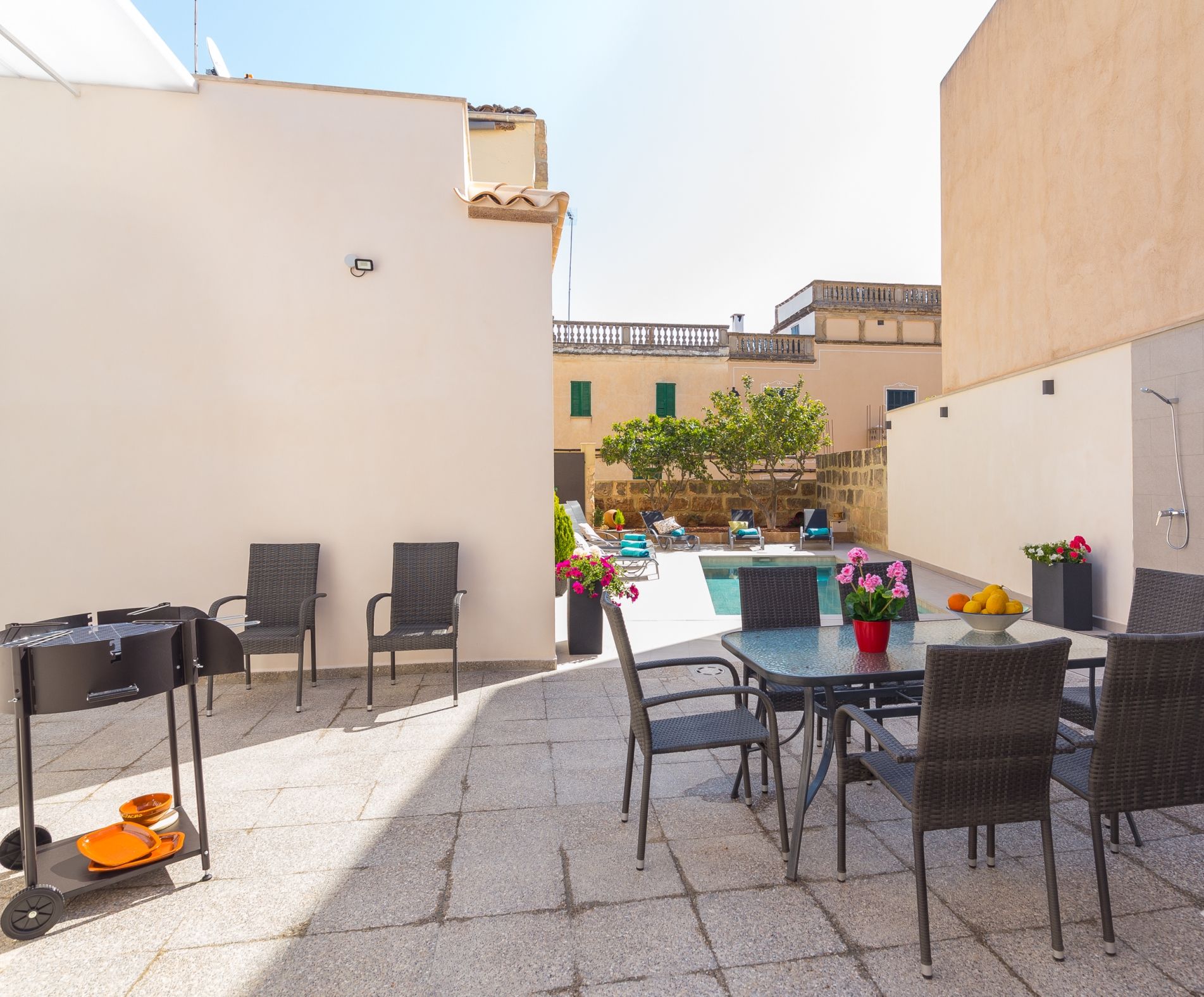 Terrassa exterior amb piscina, taula de dinar, cadires i una barbacoa.