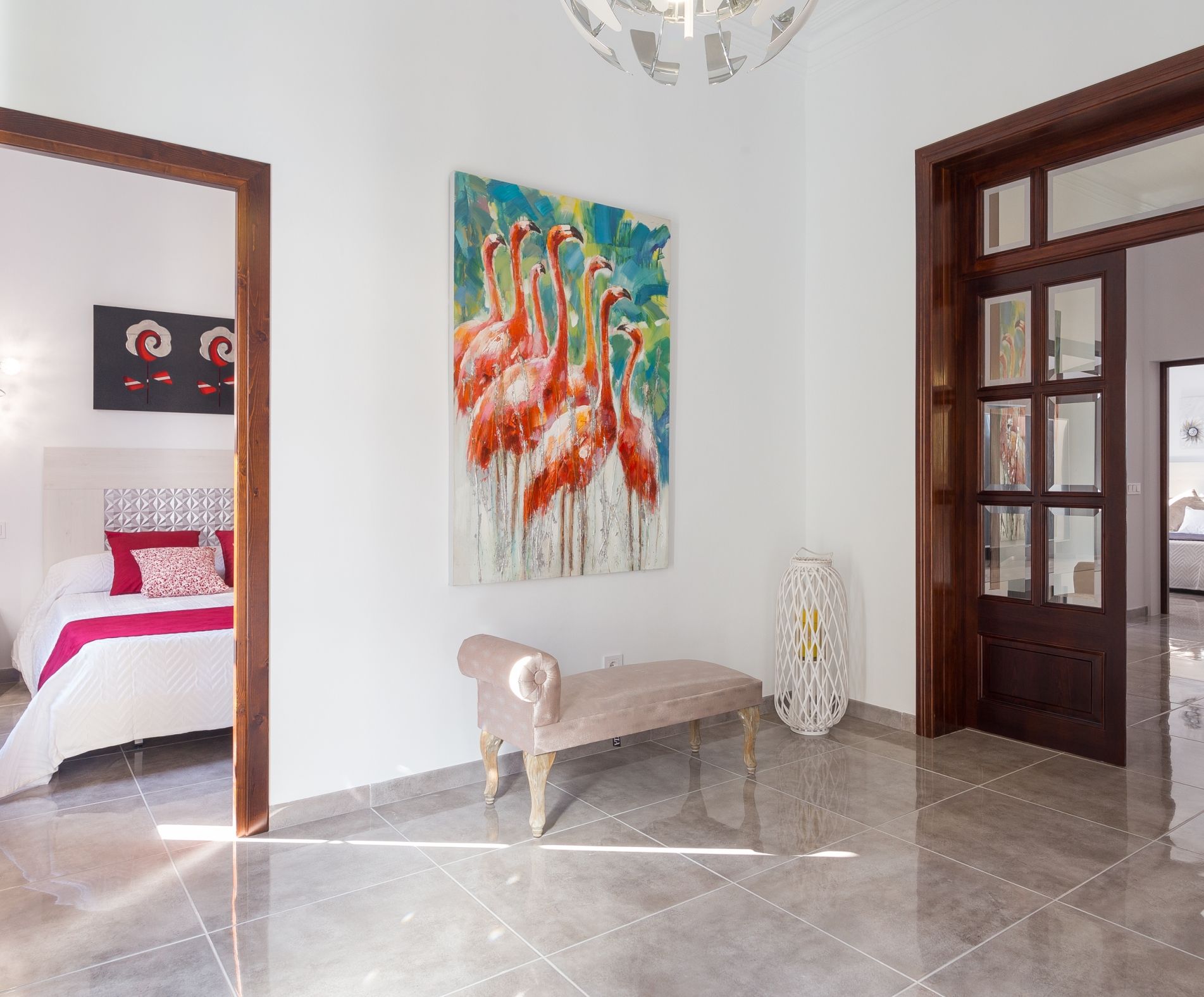 Amplia habitación con un cuadro grande de flamencos, un banco y una puerta que da a otra estancia.