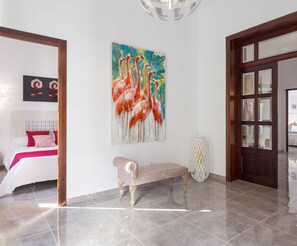 A spacious room with a large painting of flamingos, a bench, and a door leading to another room. - Son Siurana - Newtly built town house with pool in Ariany (Ariany)
