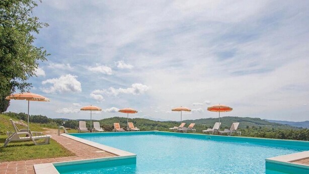 A swimming pool with lounge chairs and umbrellas, surrounded by greenery and hills. - Colline Toscane, beautiful two-room apartment for 2/4 people, lovely view and swimming pool (Casole d’elsa, siena)